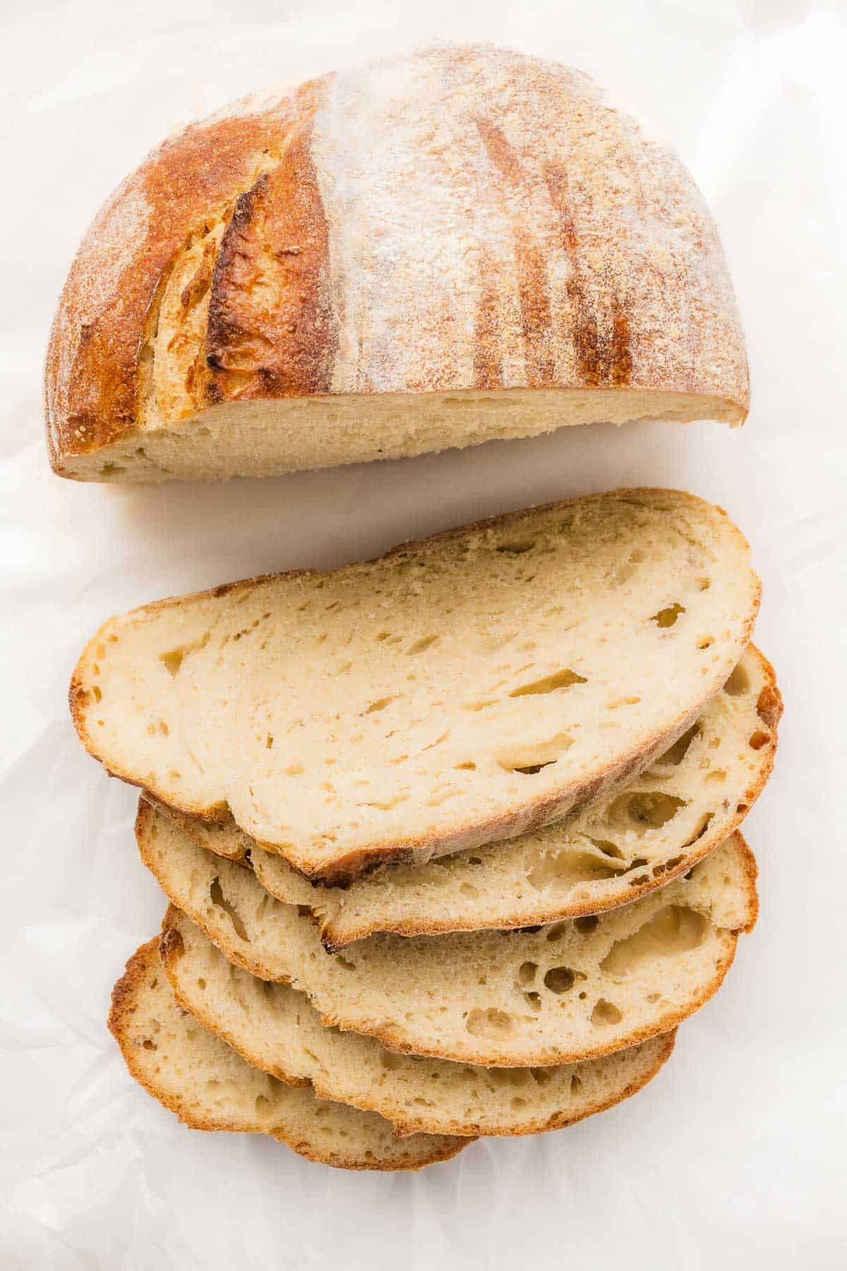 Homemade sourdough loaf with sliced bread on a white surface